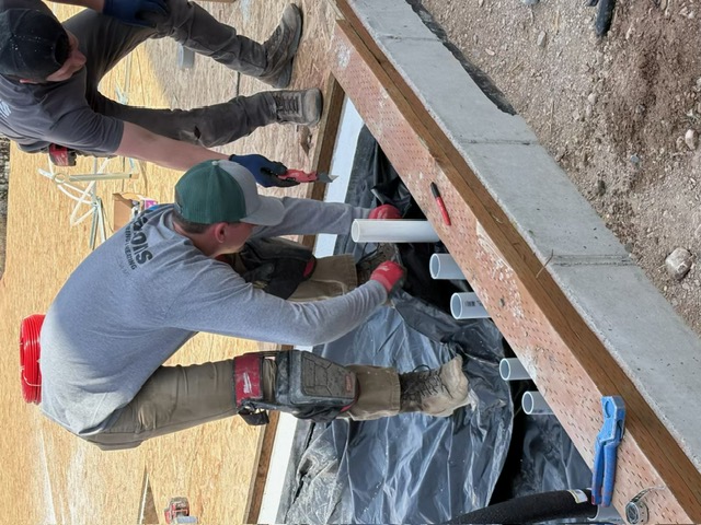 Aaron's Plumbing crew setting drain rough-in plumbing at a new construction foundation