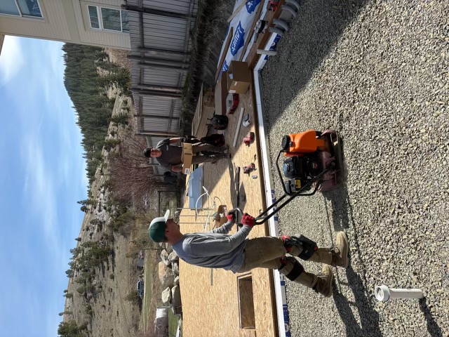 Compacting gravel for a new home foundation in the Helena valley with mountain views