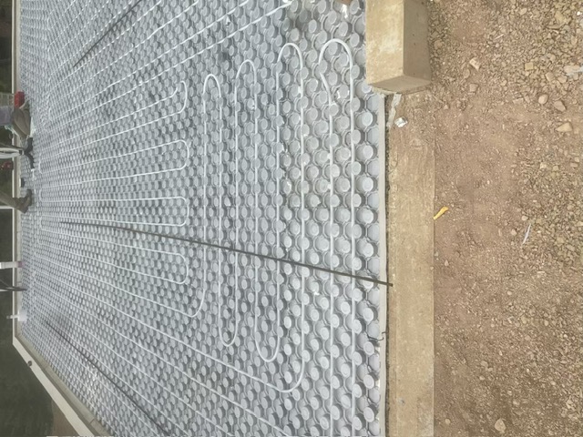 Radiant floor heating tubing laid over insulation panels before a concrete pour