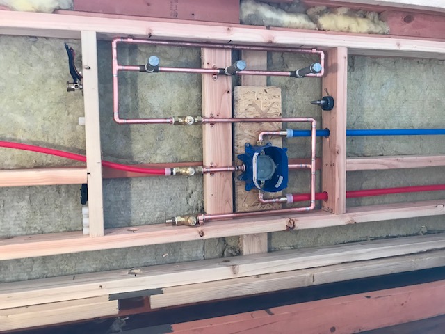 Clean shower valve and PEX rough-in plumbing in a framed bathroom wall